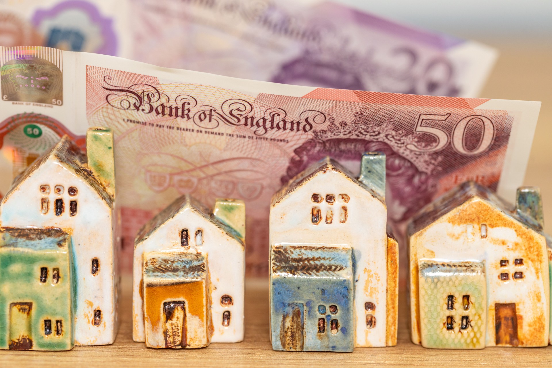 Miniature house model with banknotes on a wooden table, Home loan concept, British pound and the UK property market